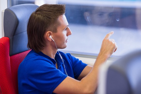 Young man talking on the phone and listen music traveling by trainの写真素材