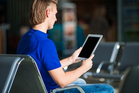 Young man with a laptop at the airport while waiting his flightの写真素材