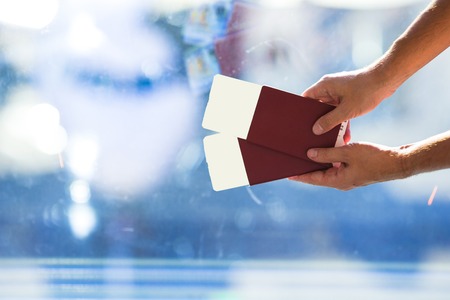 Closeup of man holding passports and boarding pass at airportの写真素材