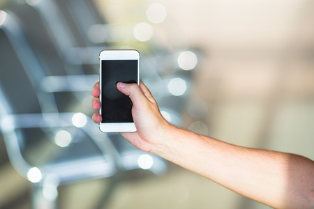 Closeup of man hand use smart phone in airport background windowの写真素材