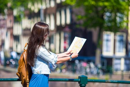 Happy young woman with a city map and a backpack smilingの写真素材