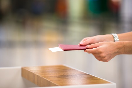 Closeup of female hands holding passports and boarding pass at airportの写真素材