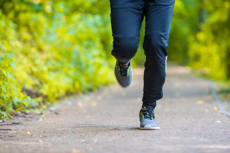 Closeup on shoe of athlete runner man feet running on roadの写真素材