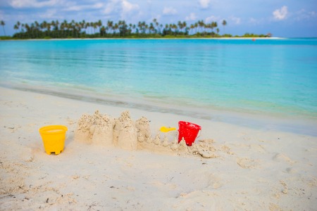 Sandcastle at white beach with plastic kids toys background the seaの写真素材