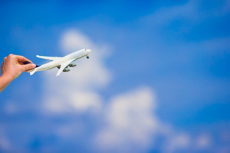 Small homemade plane in a female hand on a background of the seaの写真素材