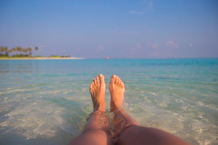 Female feet on white beach and clear waterの写真素材