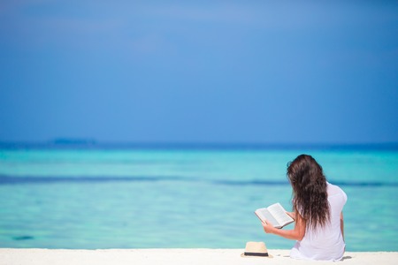 Young girl reading on tropical white beachの写真素材