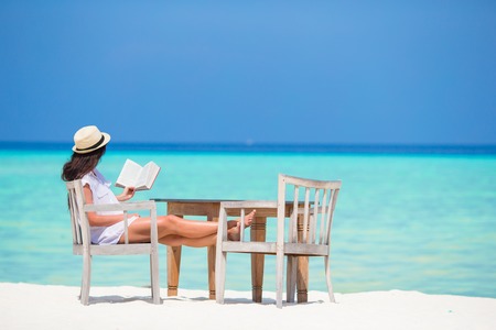 Young girl reading on tropical white beachの写真素材
