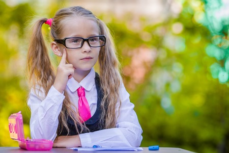 Happy little schoolgirl with notes and pencils going back to school outdoorの写真素材