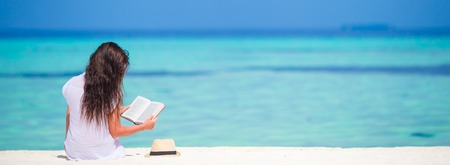 Young girl reading on tropical white beachの写真素材