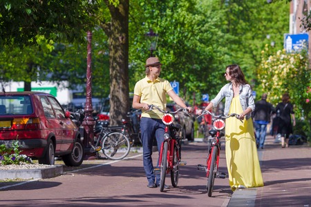 Young happy ouple on bikes in old streets in Amsterdamの写真素材