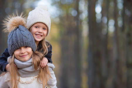 Two adorable girls in forest at warm sunny autumn dayの写真素材