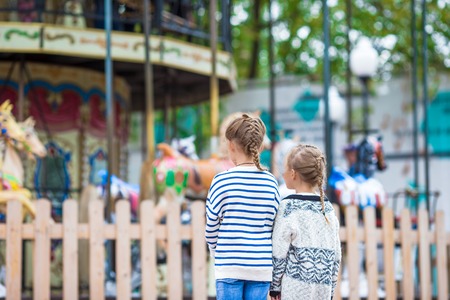 Little adorable girl on carousel at sunny day outdoorの写真素材