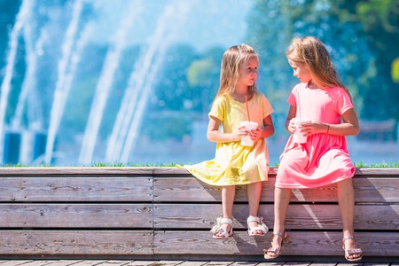 Cute little girls playing near city fountain on hot and sunny summer dayの写真素材