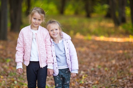 Little adorable girls at warm sunny autumn day outdoorsの写真素材