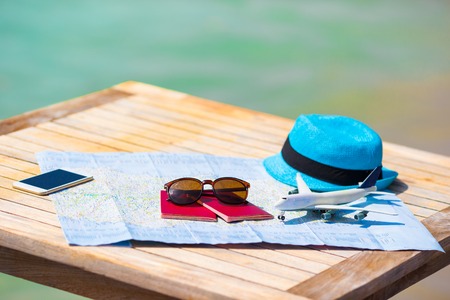 Closeup of a passport, toy airplane, sunglasses on the map
