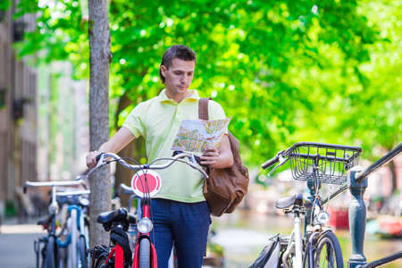Happy young man with a city map and a backpack smilingの写真素材