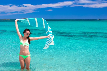 Beautiful woman having fun with beach towel during summer vacationの写真素材