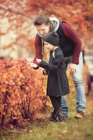 Father with cute daughter in autumn park outdoorsの写真素材