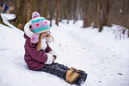 Portrait of little adorable happy girl in the snow sunny winter dayの写真素材