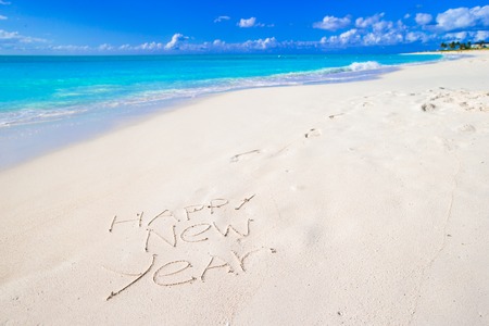 Santa Hat on white sandy beach and Merry Christmas written in the sand
