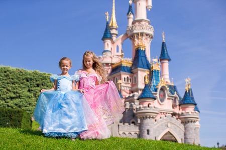 Little cute happy girls in beautiful princess at fairy-tale park