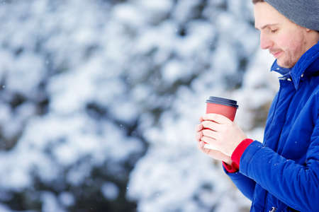 Happy man drinking coffee outdoors in winter time