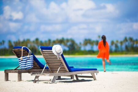 Back view of young beautiful woman relaxing at beach chairsの写真素材