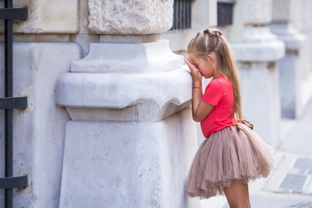 Little fashion girl playing hide and seek on street in Paris outdoorsの写真素材