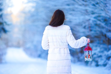 Young beautiful happy woman with red Christmas lantern in the snowの写真素材