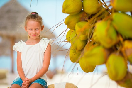 Cute little girl holding coconut cocktail on beachの写真素材