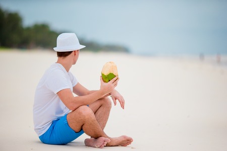 Man enjoy beach vacation and drinking coconutの写真素材