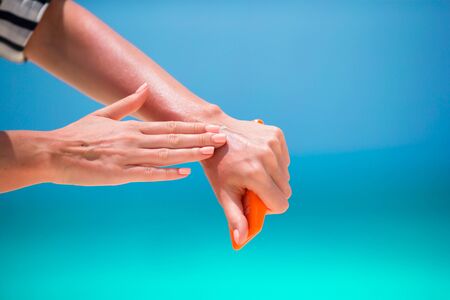 Woman hands putting sunscreen from a suncream bottle background the seaの写真素材
