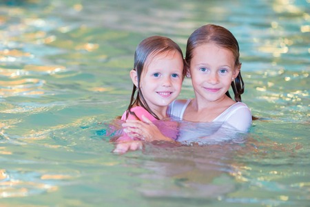 Adorable little girls playing in outdoor swimming poolの写真素材