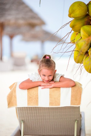 Cute little girl holding coconut cocktail on beachの写真素材
