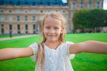 Adorable little girl taking selfie with mobile phone outdoors in Paris, Franceの写真素材