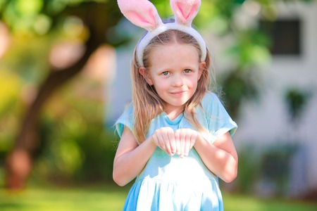 Adorable girl wearing bunny ears holding basket with Easter eggs