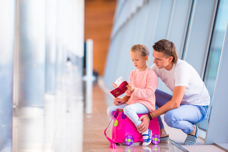 Dad and little daughter looking out the window at airport terminalの写真素材