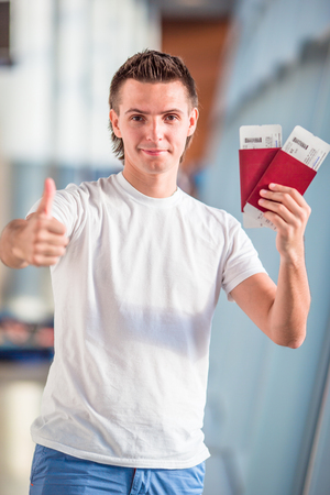 Closeup of male hands holding passports and boarding pass at airportの写真素材
