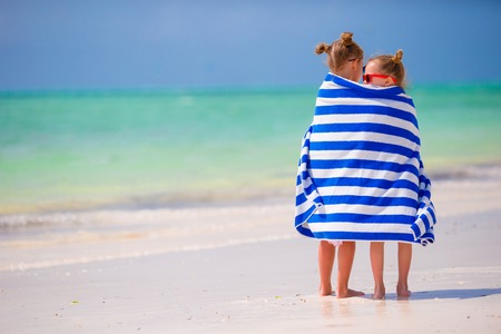 Cute little girls at beach covered with towelの写真素材