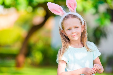 Adorable girl wearing bunny ears holding basket with Easter eggs