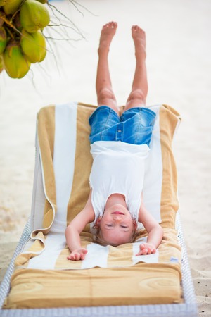 Cute little girl holding coconut cocktail on beachの写真素材