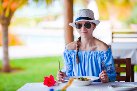 Young woman having breakfast at outdoor cafe on vacationの写真素材