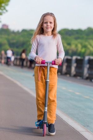 Two little girls riding on scooter in the park outdoorの写真素材