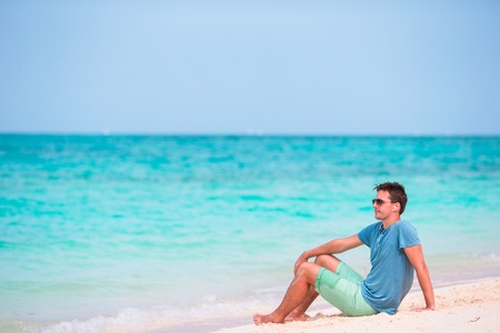 Young beautiful man listening to music on white  beachの写真素材