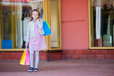 Pretty smiling little girl with shopping bagsの写真素材