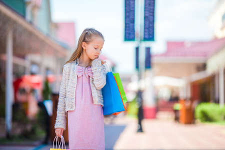 Adorable smiling little girl with shopping bags in big mallの写真素材