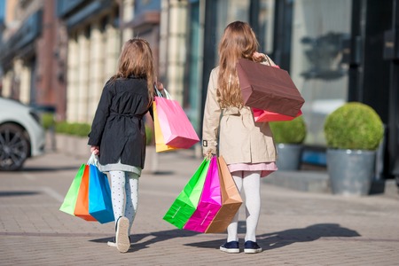 Pretty smiling little girls with shopping bagsの写真素材