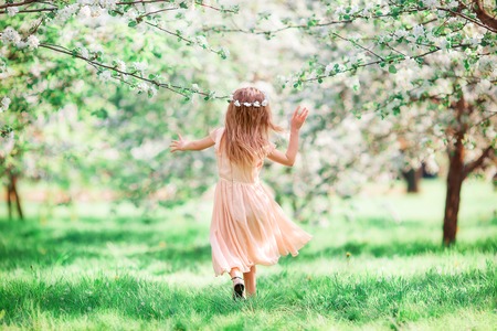Adorable little girl in blooming cherry garden on beautiful spring dayの写真素材