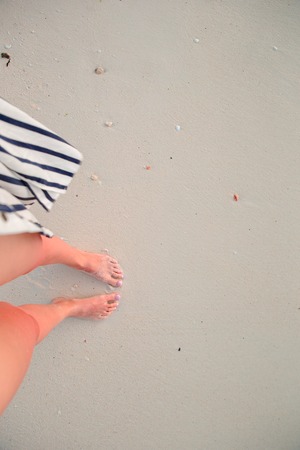 Close up of female feet on white sandy beach